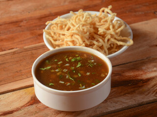 Manchow soup, indo chinese dish served over a rustic wooden background, selective focus