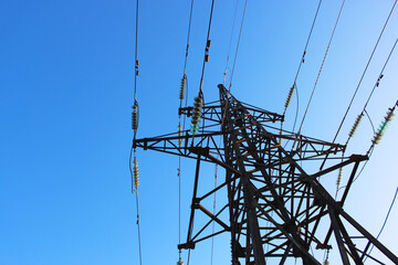 High voltage transmission tower line against blue sky, bottom view. iron construction.