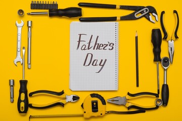 Tools top view on yellow background. Father's day card with tools. Plier, open wrenches, screwdrivers and staple gun in a cirlce.