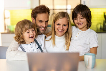 Wall Mural - Happy young family using laptop at home
