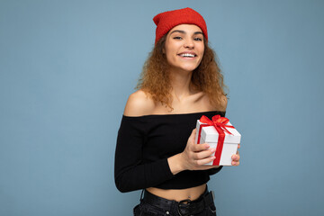 Wall Mural - Shot of attractive positive smiling young woman isolated over colourful background wall wearing everyday trendy outfit holding gift box and looking at camera