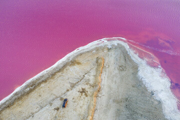 Wall Mural - aerial view to sand spit in pink lake in Ukraine with car and copy space