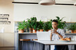 © Paul Bradbury/Caia Image - Businesswoman with coffee working at laptop in morning office lounge