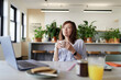 © Paul Bradbury/Caia Image - Happy businesswoman drinking coffee at laptop in office lounge