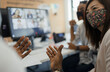 © Paul Bradbury/Caia Image - Business people in face masks talking and video conferencing in office