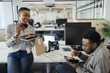 © Paul Bradbury/Caia Image - Happy business people eating takeout lunch at desk in open plan office