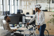 © Paul Bradbury/Caia Image - Businesswoman with bicycle talking to businessman in office