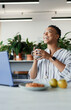 © Paul Bradbury/Caia Image - Happy businesswoman with coffee laughing at laptop in office