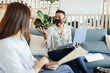 © Paul Bradbury/Caia Image - Businesswomen in face masks meeting on office sofa