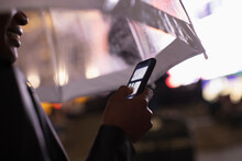 Close Up Young Woman Using Smart Phone Under Umbrella At Night