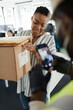 © Paul Bradbury/Caia Image - Businesswoman receiving packages from courier with smart phone
