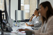 © Paul Bradbury/Caia Image - Businesswoman talking on telephone at computer in office window