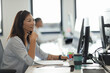 © Paul Bradbury/Caia Image - Smiling businesswoman in headset working at computer in office