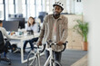© Paul Bradbury/Caia Image - Businessman walking bicycle in office