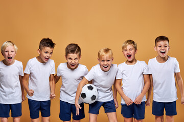 Wall Mural - kids soccer players celebrate a winning in school sports tournament, studio portrait of happy joyful kids in uniform engaged in football