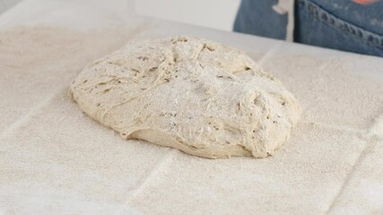 Wall Mural - A woman divides the dough in two on the countertop with flour for making bread. Cooking pizza. Baking bread. Cooking the ciabatta. Italian bread. Rye bread. 4K