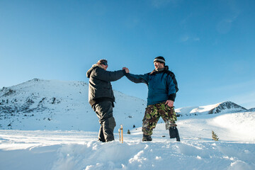 Wall Mural - Handshake of two friends in the snowy mountains