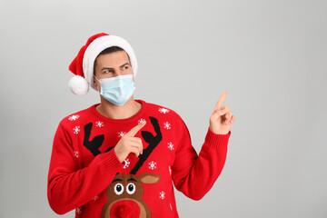 Wall Mural - Man wearing Santa hat and medical mask on grey background