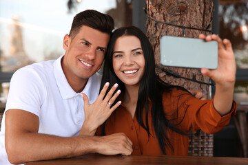 Poster - Lovely couple taking selfie after they got engaged in outdoor cafe