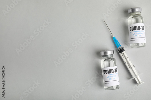 Obraz Dibond Vials with coronavirus vaccine and syringe on light background, flat lay. Space for text