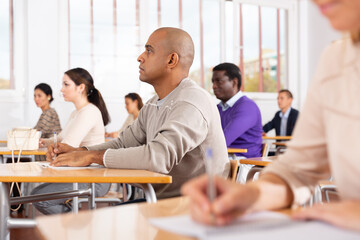 Canvas Print - Portrait of attentive focused Latino on lesson in school auditorium. Adult learning and education concept