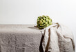 © The Picture Pantry - Artichoke on the table covered with a gray linen tablecloth.