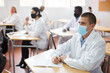 © JackF - Focused man studying in classroom with colleagues medicals in protective face masks for disease prevention during training program for health workers