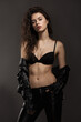 © Alexander - Beautiful sexy girl in black leather pants and an open leather jacket posing in the studio on a gray background