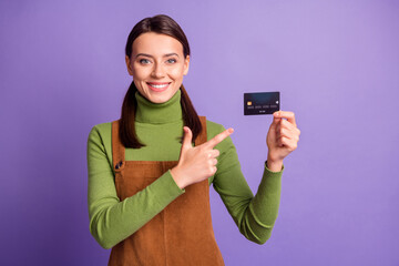 Poster - Portrait of lovely cheerful content girl holding in hands demonstrating bank card advert isolated over bright violet color background