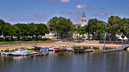 Wall Mural - Barges on the Maine river at Angers and the La Trinité church among the trees. Angers is a commune in the Maine-et-Loire department, Pays de la Loire region, in western France 