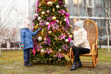 Smiling mother and daughter near Christmas tree