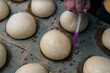 © Sergey - Close-Up of fresh Hamburger Buns, dough. bakery products. production and cooking. Silicone and plastic brush with an egg. Woman hands