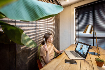 Wall Mural - young woman in domestic suit having a video connection with colleagues, working on laptop from a coz