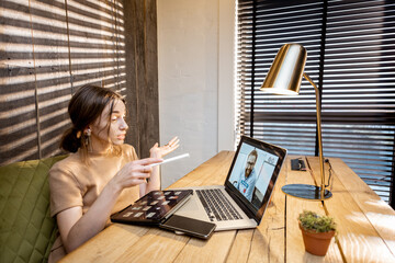 Wall Mural - young woman in domestic suit having a video connection with colleagues, working on laptop from a coz