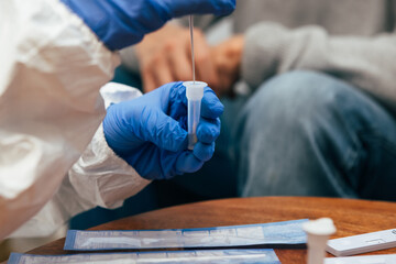 Wall Mural - Close up of medical staff hands introducing the nasal swab to the buffer tube to take a nasal culture sampling from a senior man at his home, on a home visit. Rapid Antigen Test for Covid-19.