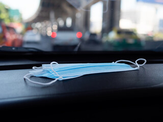 Medical face mask in car with auto vehicle and car bokeh light on road. Health care concept.