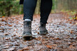 Close up of hiker walking down the wet forest path. Person with dirty hiking shoes on the footpath outdoors.