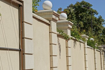 Wall Mural - one large concrete yellow brown fence wall in green vegetation with white round lanterns outside