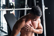 An asian male bodybuilder suffers a torn pectoral muscle while doing heavy incline bench presses on a Smith Machine at a gym or fitness center. A common workout injury
