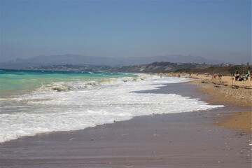 evocative image of a sandy beach with a sea of many colors and clear skies
