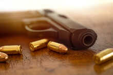 Gold Bullets And Pistol On Wooden Surface