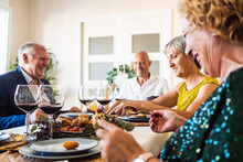Senior People Enjoying Tasty Dish While Sitting At Table During Christmas Holiday