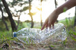 © David Munoz/ADDICTIVE STOCK - Side view of crop anonymous female volunteer picking plastic bottle in woods while cleaning natural environment from garbage