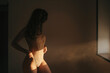 © Gustavo Pozo/ADDICTIVE STOCK - Side view of curvy female wearing lace bodysuit standing in room lit by sunlight
