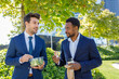 © Ignacio Ferrandiz/ADDICTIVE STOCK - Positive young diverse coworkers in formal clothes smiling while having lunch break together on street on sunny day