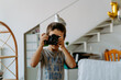 © Jake Jakab/ADDICTIVE STOCK - Content boy wearing casual shirt standing in modern apartment and shooting photo on professional photo camera
