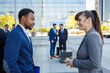 © Ignacio Ferrandiz/ADDICTIVE STOCK - Side view of young positive multiracial colleagues in classy suits standing together on street and discussing business strategy after work