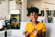 © Jake Jakab/ADDICTIVE STOCK - Cheerful young African American female blogger recording video on smartphone while preparing content for social networks at home