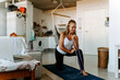 © Jake Jakab/ADDICTIVE STOCK - Full length young content sportswoman in activewear performing arms exercise by using elastic band while working out on mat at home