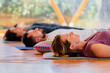 © Javier De La Torre/ADDICTIVE STOCK - Side view of people with closed eyes lying on mats after practicing yoga on wooden floor in class